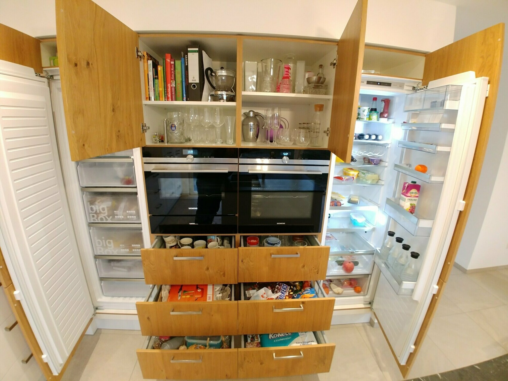 Küche mit offenen Holzschränken, zwei Backöfen, Gläserregal und offene Kühlschränke