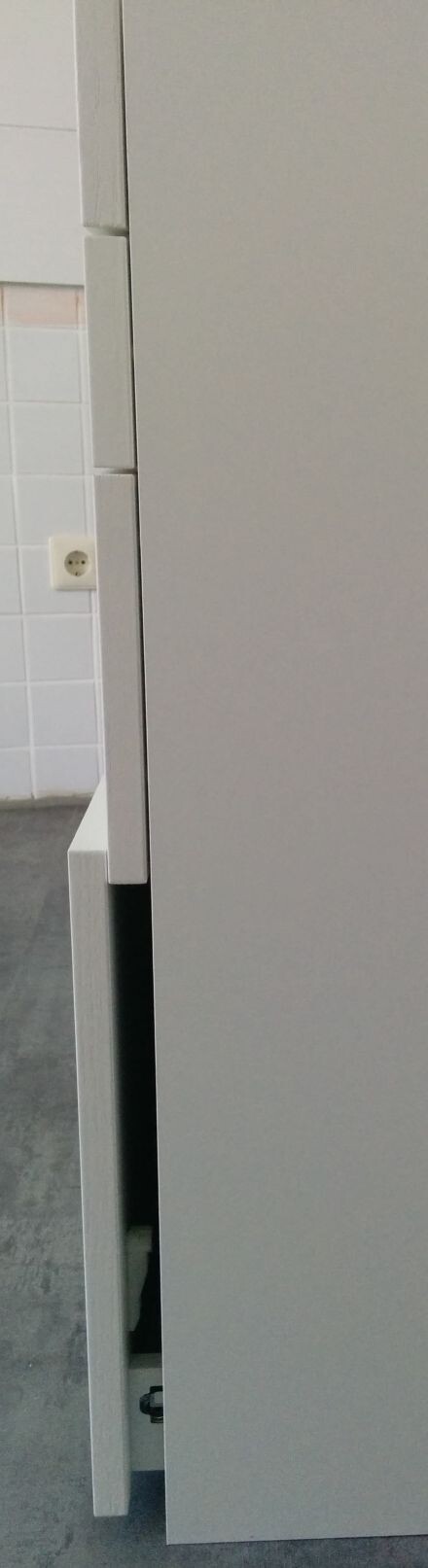 Moderne Küchenschrank-Schublade offen neben Fliesenwand und Steckdose
