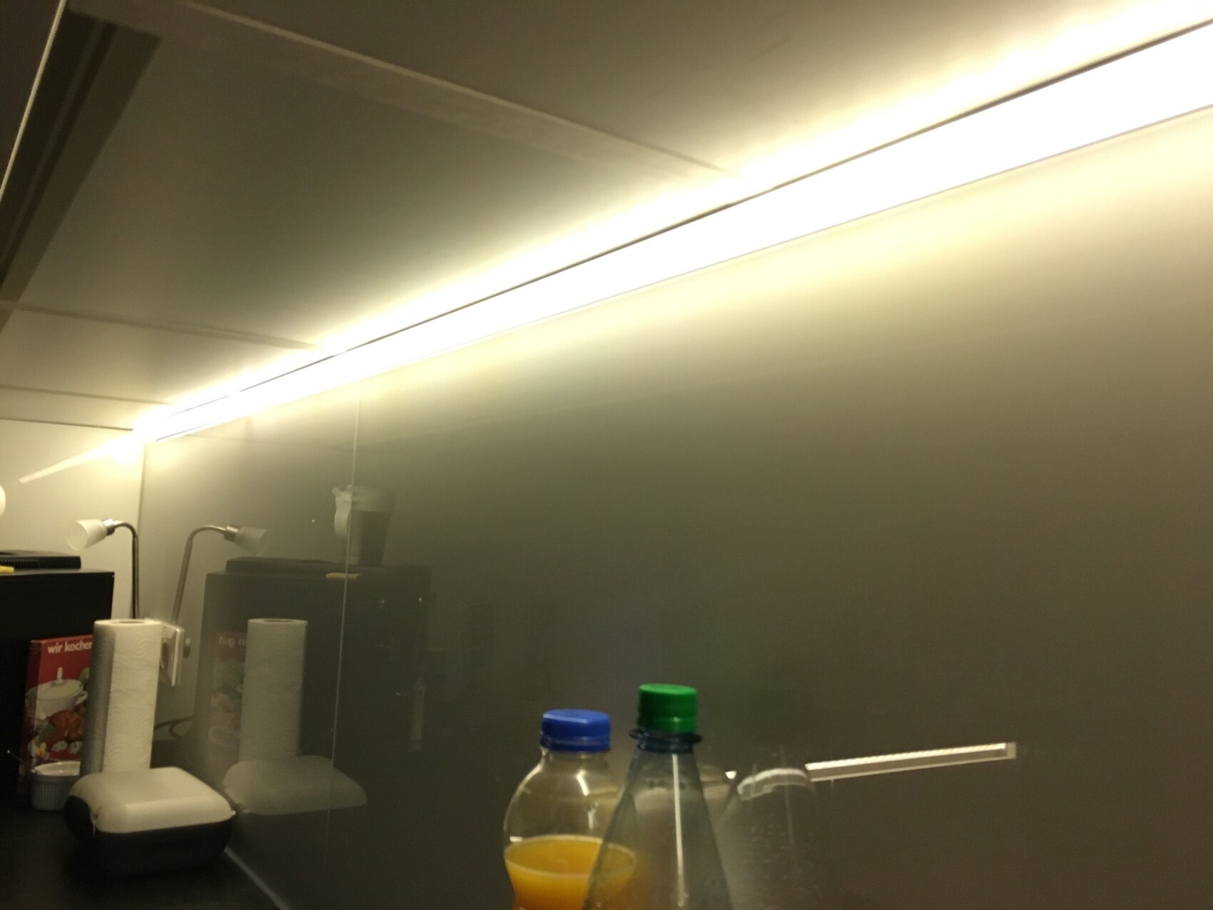Küchenbereich mit heller Unterbau-Lichtleiste über der Arbeitsfläche und Glasrückwand