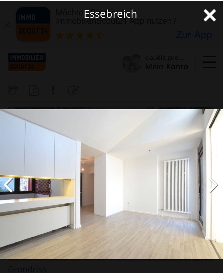 Heller moderner Kuechen- und Wohnbereich mit weisser Einbaukueche und hellem Holzboden