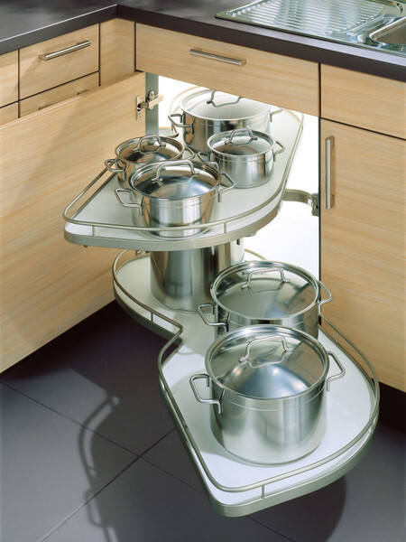 Ausziehbarer Eckschrank in der Küche mit Edelstahl-Töpfen und Deckeln auf mehreren Ebenen.