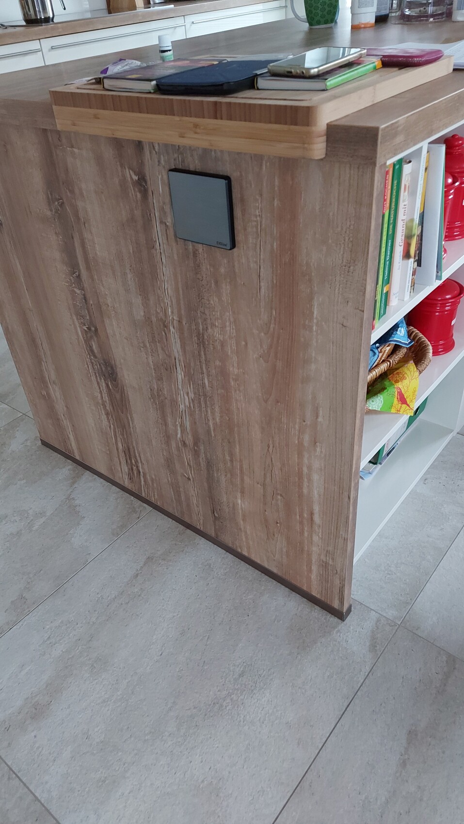 Holz-Kücheninsel mit Regalseite, Bücher, rote Vorratsbehälter und Notizblöcke auf der Platte.