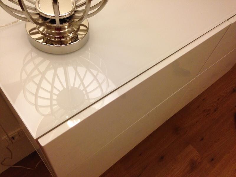 Moderne Lampe auf glänzender weißer Glasoberfläche im Wohnzimmer.