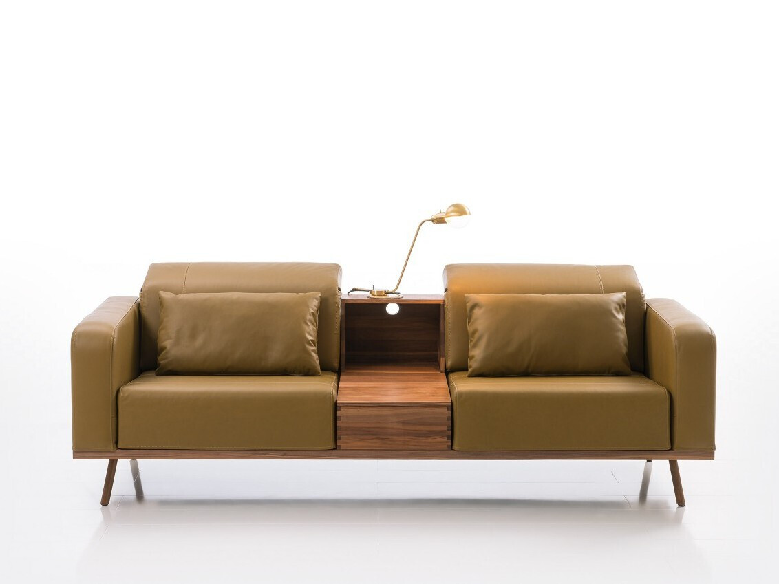 Zweisitzer-Ledersofa in Braun mit zentraler Holzkonsole und Goldlampe zwischen den Sitzen.
