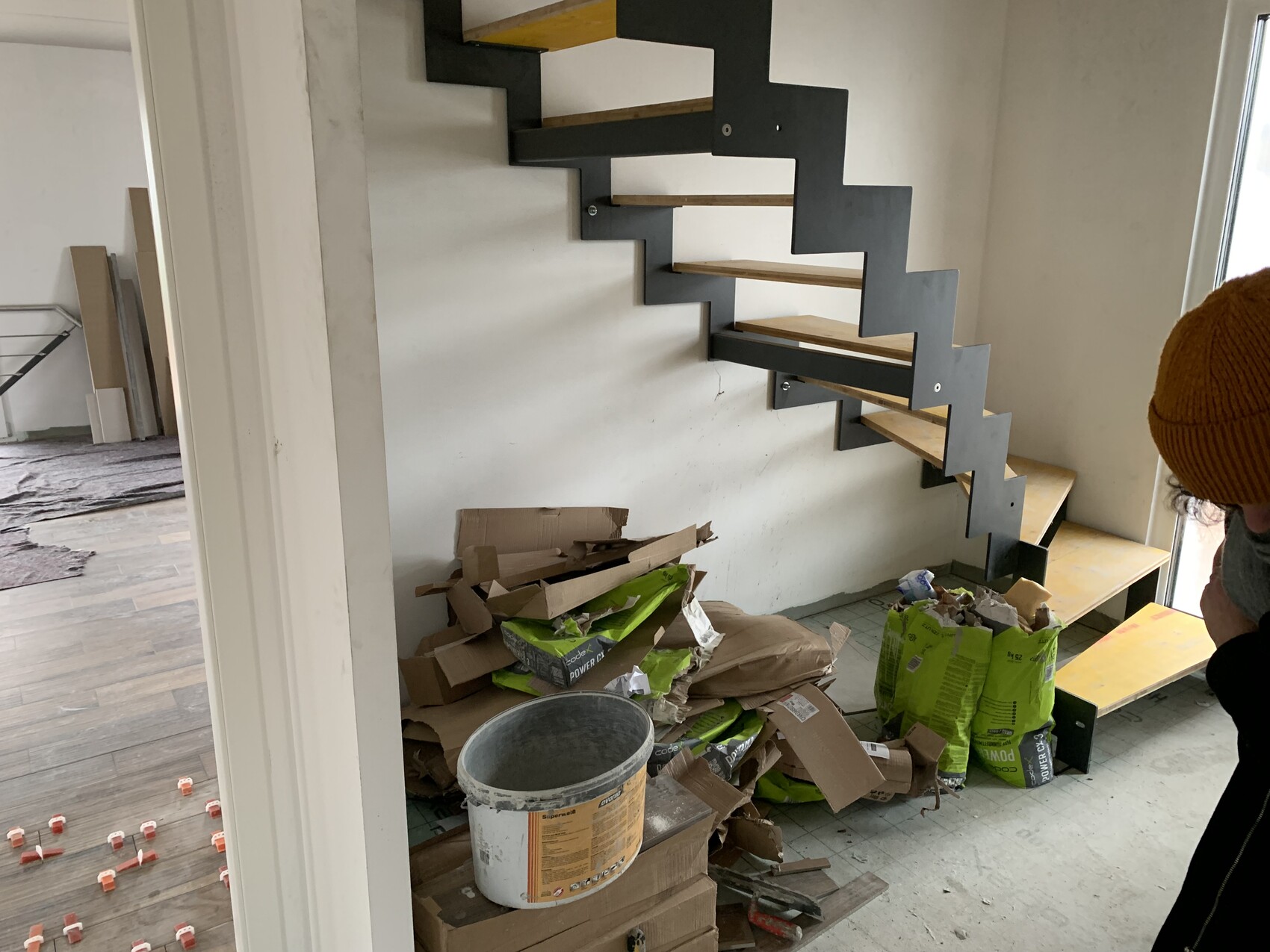 Zickzack-Treppe aus schwarzem Stahl mit Holzstufen; Bauabfall, Eimer und Säcke.