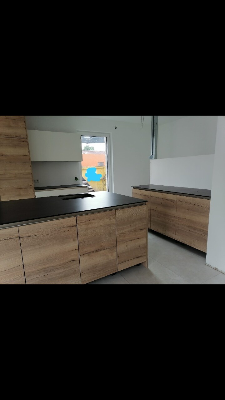 Küche mit Holzfronten, schwarzer Arbeitsplatte, Insel und Unterschränke.