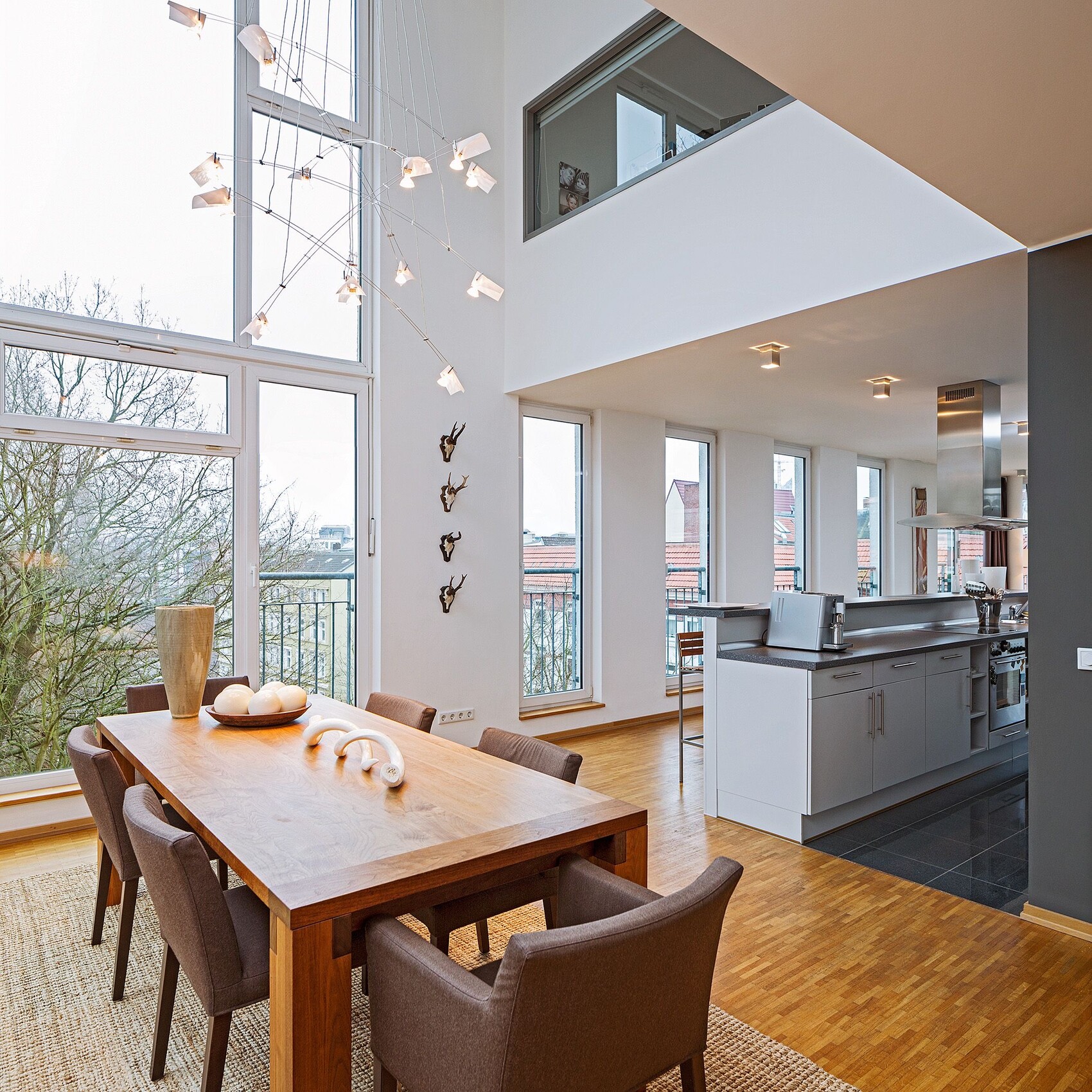 Offener Küchen- und Essbereich mit Holztisch, modernen Stühlen und großer Fensterfront.