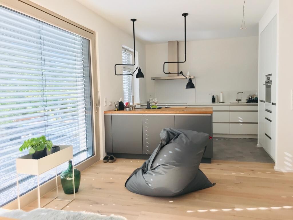 Moderne Küche: graue Schränke, Holz-Arbeitsfläche, schwarze Pendelleuchten, grauer Sitzsack.