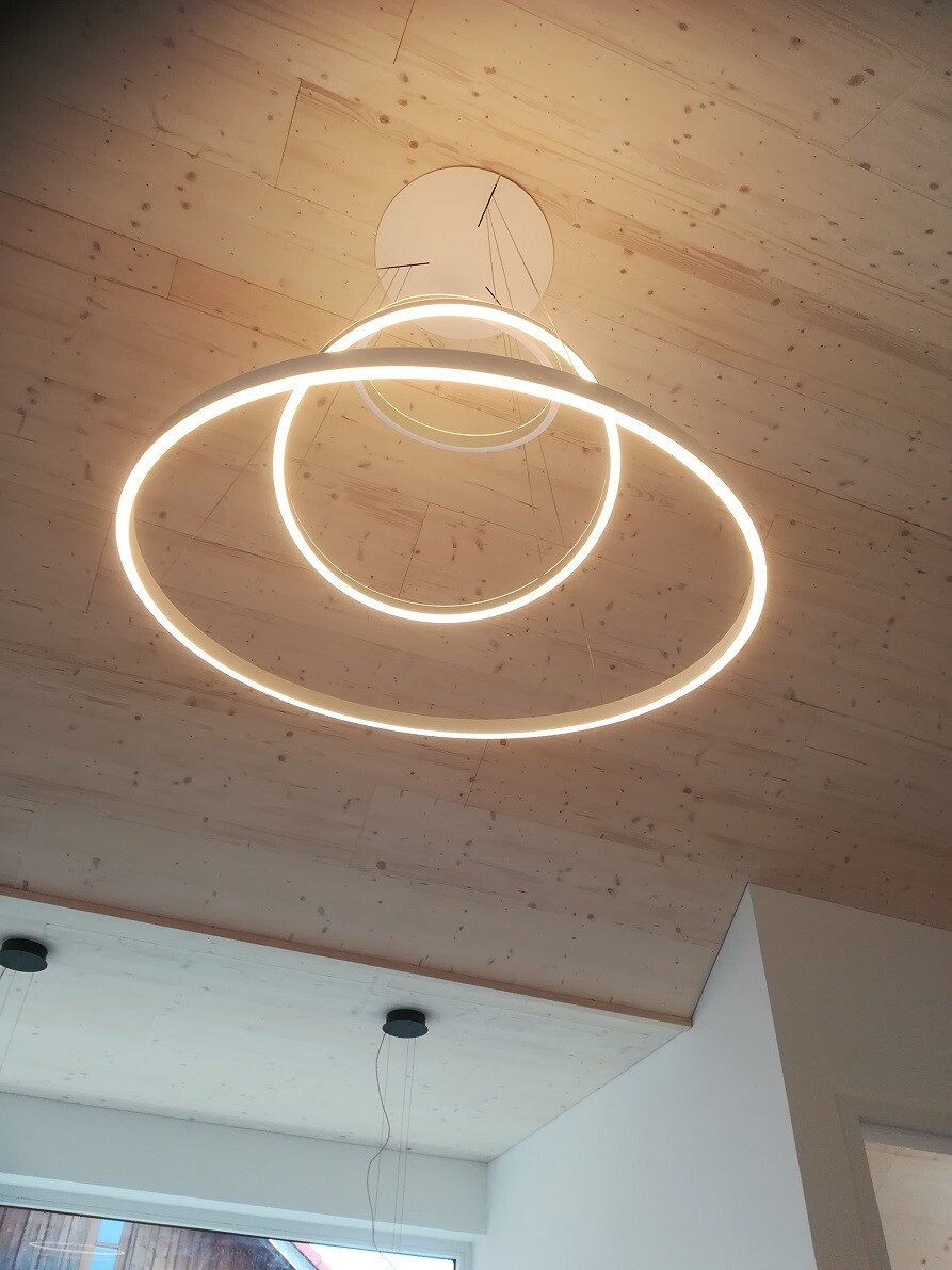 Moderne LED-Ringlampe mit zwei Kreisen an der Holzdecke, von unten gesehen