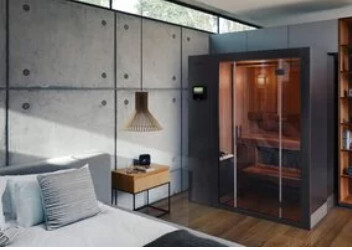 Moderne Sauna mit Glasfront im Wohnbereich neben Couch und Holzboden.