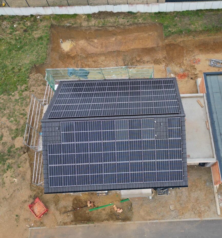 Luftaufnahme eines Hauses mit Solarpanelen auf dem Dach; Bauarbeiten im Hof.