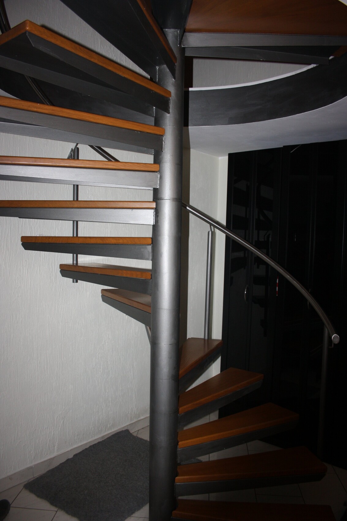 Moderne spiralförmige Innentreppe aus Metall mit Holzstufen im Innenraum