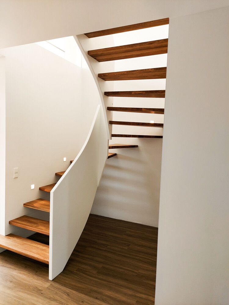 Moderne weiße Treppe mit geschwungener Form, offenen Holztreppenstufen und Holzfußboden.