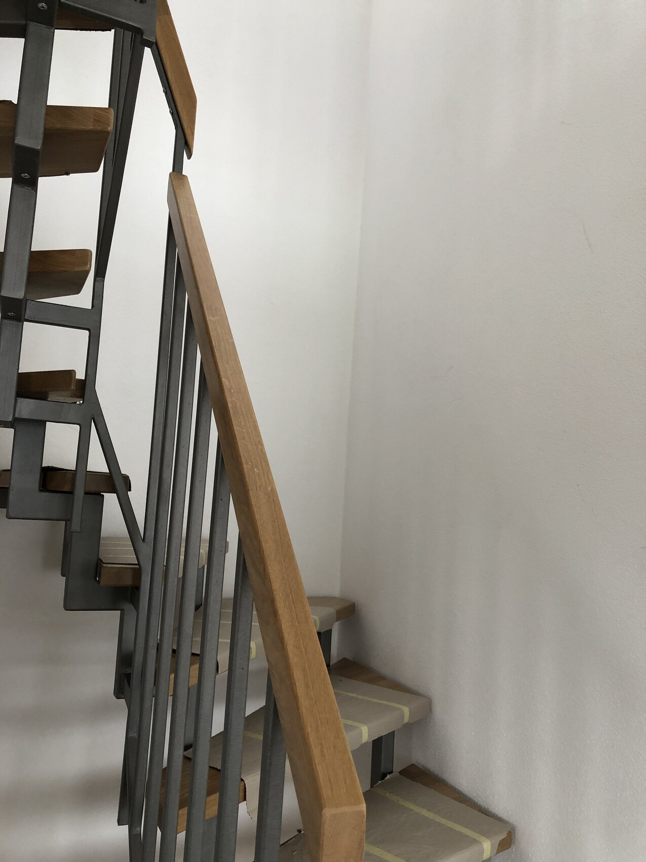 Moderne Treppe mit Stahlgeländer und Holzstufen in hellem Treppenhaus.