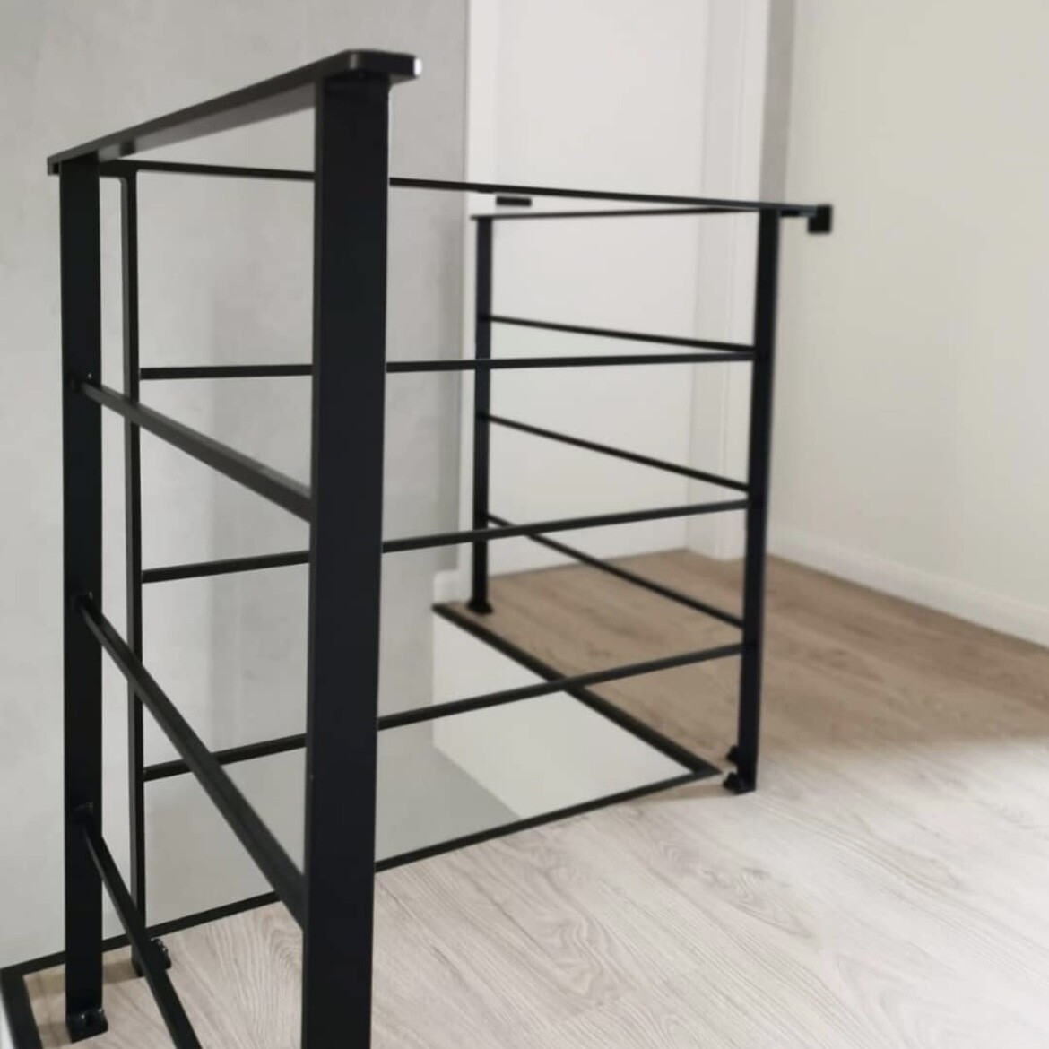 Schwarzes Metallgeländer mit mehreren horizontalen Stäben im hellen Innenraum.