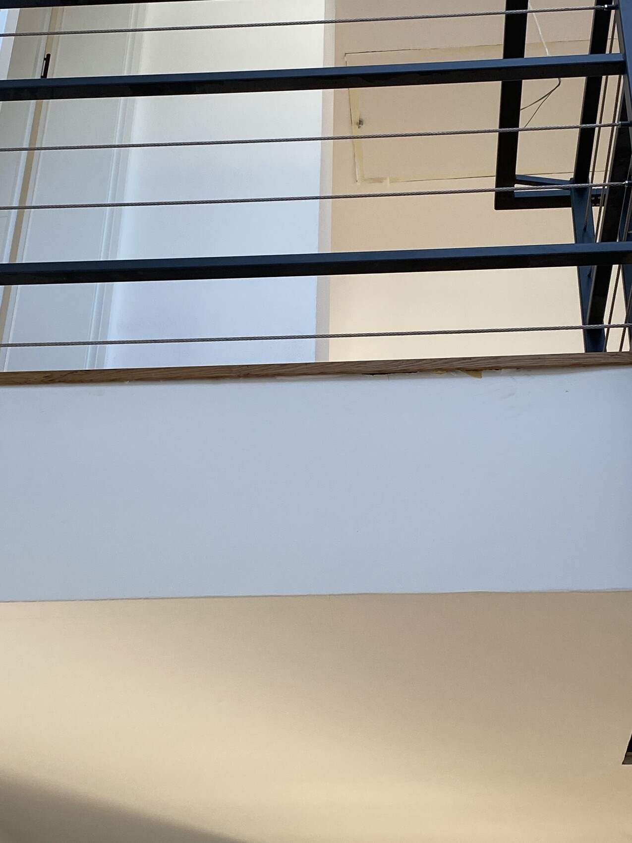 Innenraum-Balkon mit Geländer aus Drahtseilen und schwarzen Metallpfosten.