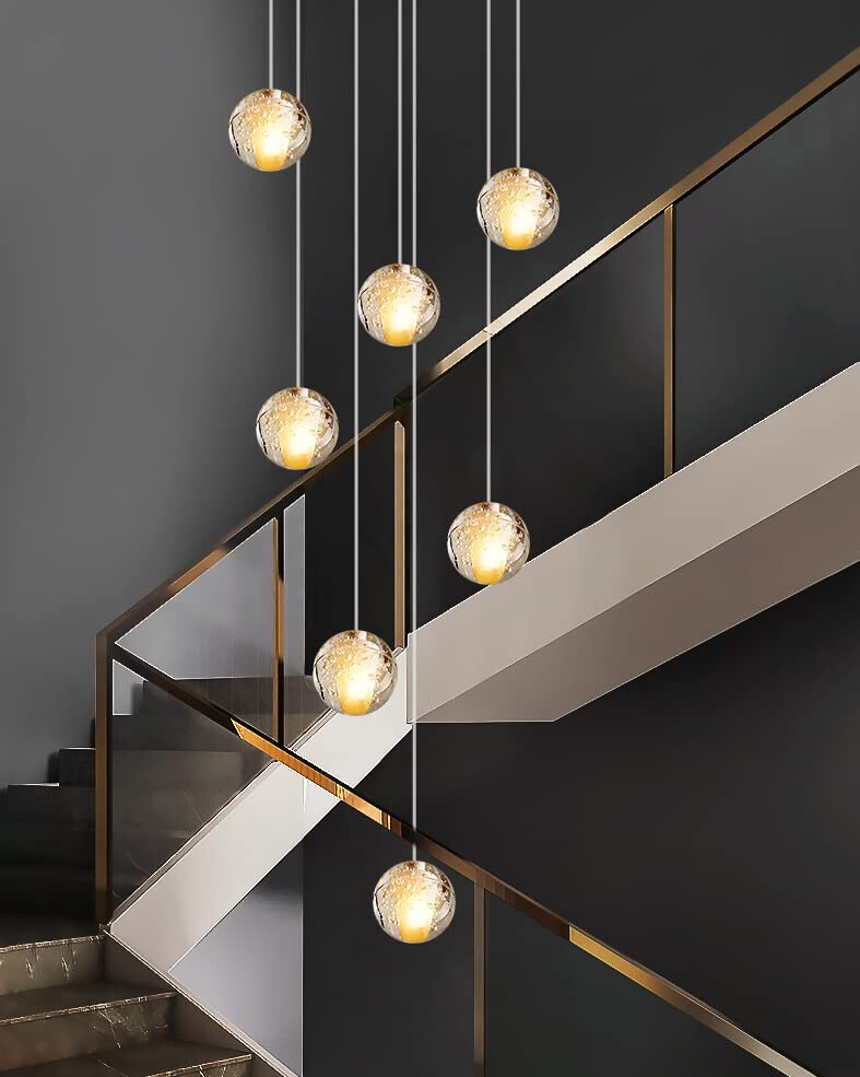 Moderne Treppe mit Glasgeländer und hängenden Glaskugellampen mit goldenen Akzenten.