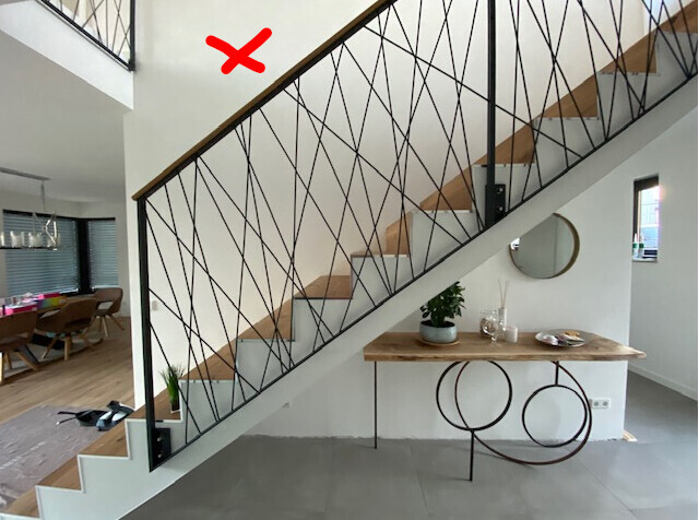 Modernes Treppengeländer mit diagonalem Metallgitter; Blick auf Esstisch, Pflanze und Spiegel.