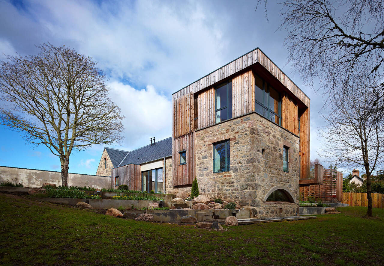Außenansicht eines modernen Hauses mit Steinbasis, Holzverkleidung und Garten