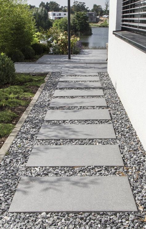 Gartenweg mit quadratischen Betonplatten auf Kies neben Haus, Richtung See.