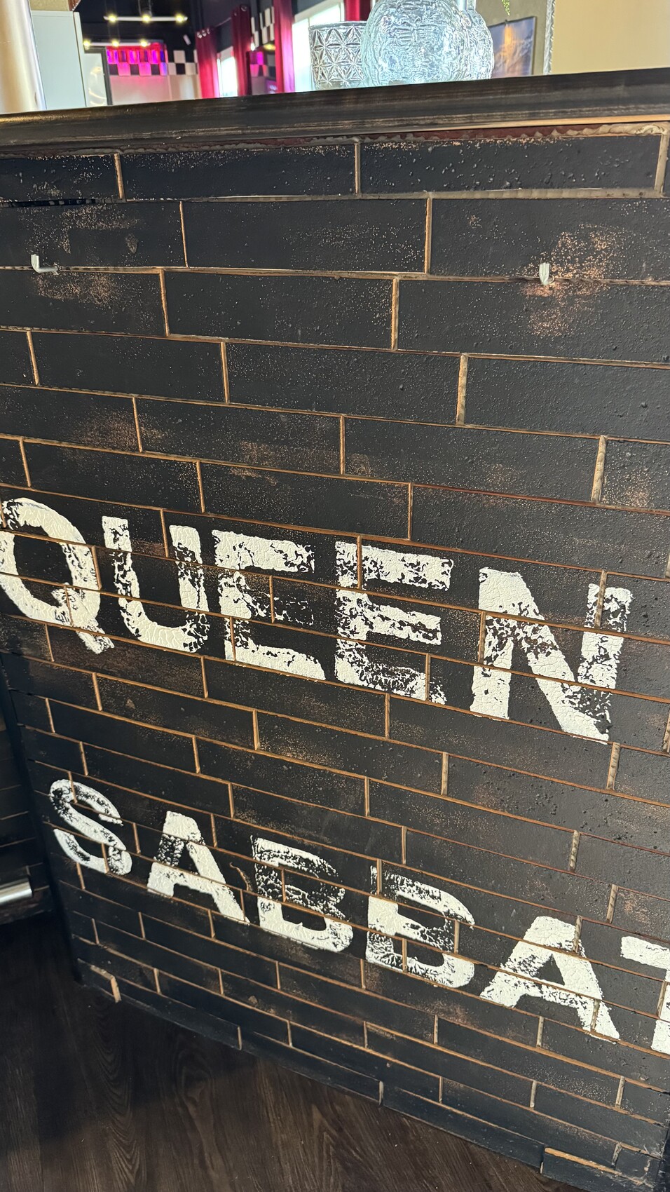 Dunkle Steinwand aus Ziegeln mit verblasster weißer Schrift in Bar-Interieur