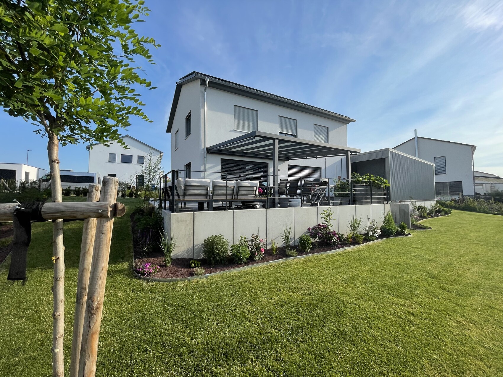 Moderne weiße Hausvilla mit großer Terrasse, Pergola und gepflegtem Garten