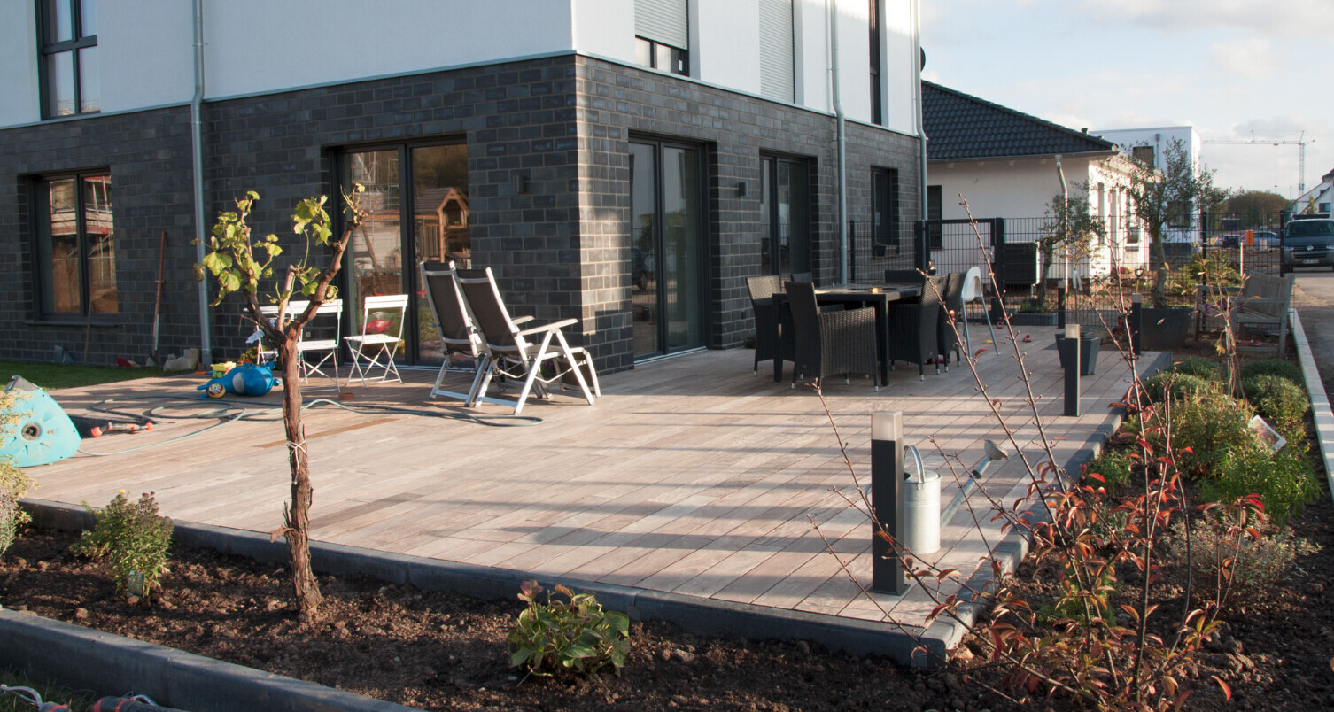 Moderne Haus-Terrasse mit Holzdeck, Lounge-Sets, Tischgruppe und Pflanzen