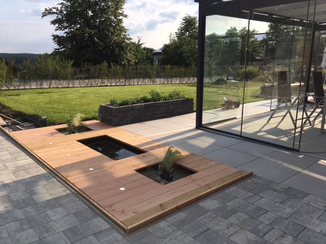 moderne-terrasse-holzdeck-wasserbecken-glaswand.jpeg