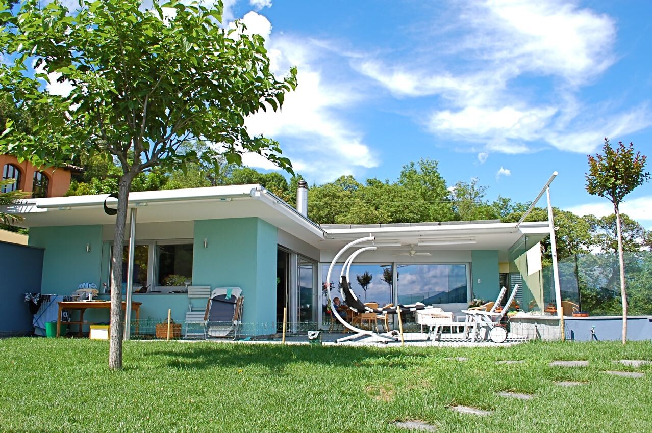 Modernes Einfamilienhaus mit Terrasse, Lounge-Möbeln und grünem Garten