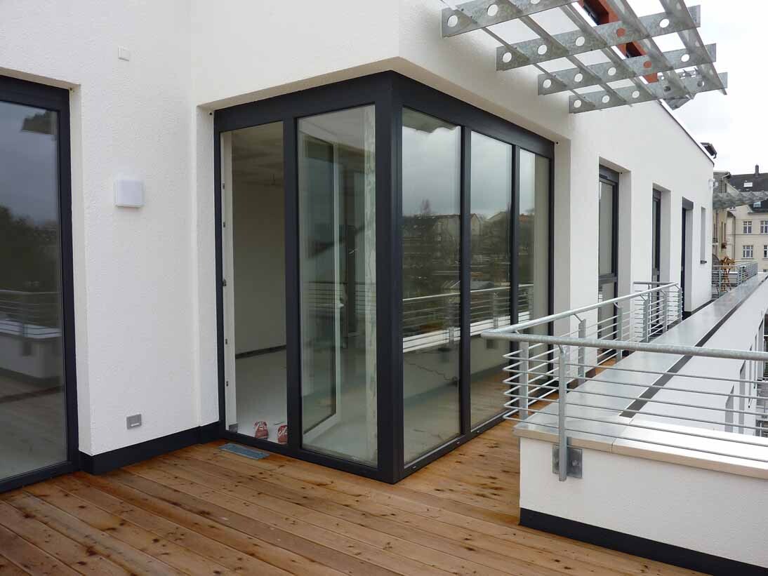 Moderne Terrasse mit großen Glasschiebetüren, Holzdeck und Geländer