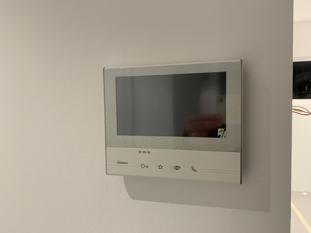 Wandmontierte Video-Türsprechanlage mit Bildschirm und Bedienelementen.