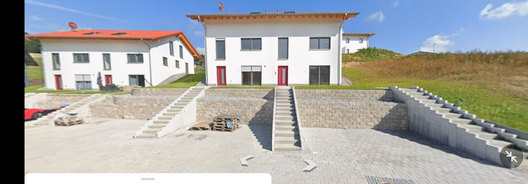 Moderne weiße Häuser auf terrassiertem Hof mit Steinmauern und Treppen