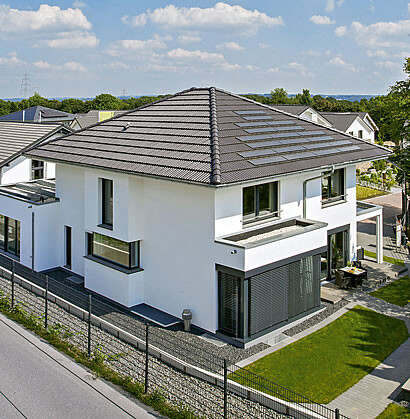 Moderne weisse Hausfassade mit dunklem Ziegeldach, Terrasse und Garten