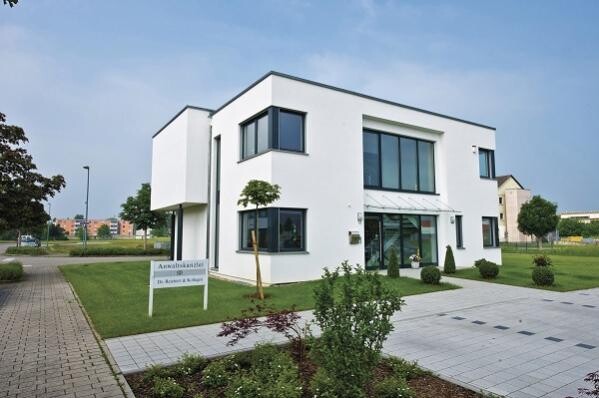 Moderne weisse zweigeschossige hausfassade mit grossen fenstern, garten und gepflasterter einfahrt