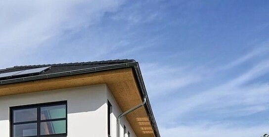 Außenansicht eines modernen weißen Hauses mit Dachüberstand und Fenster gegen blauen Himmel.