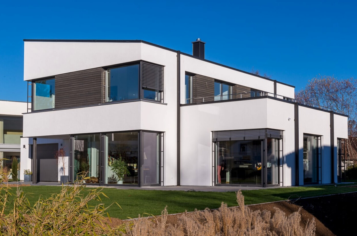 Modernes weisses Architektenhaus mit großen Glasfronten, Balkonen und Gartenfläche