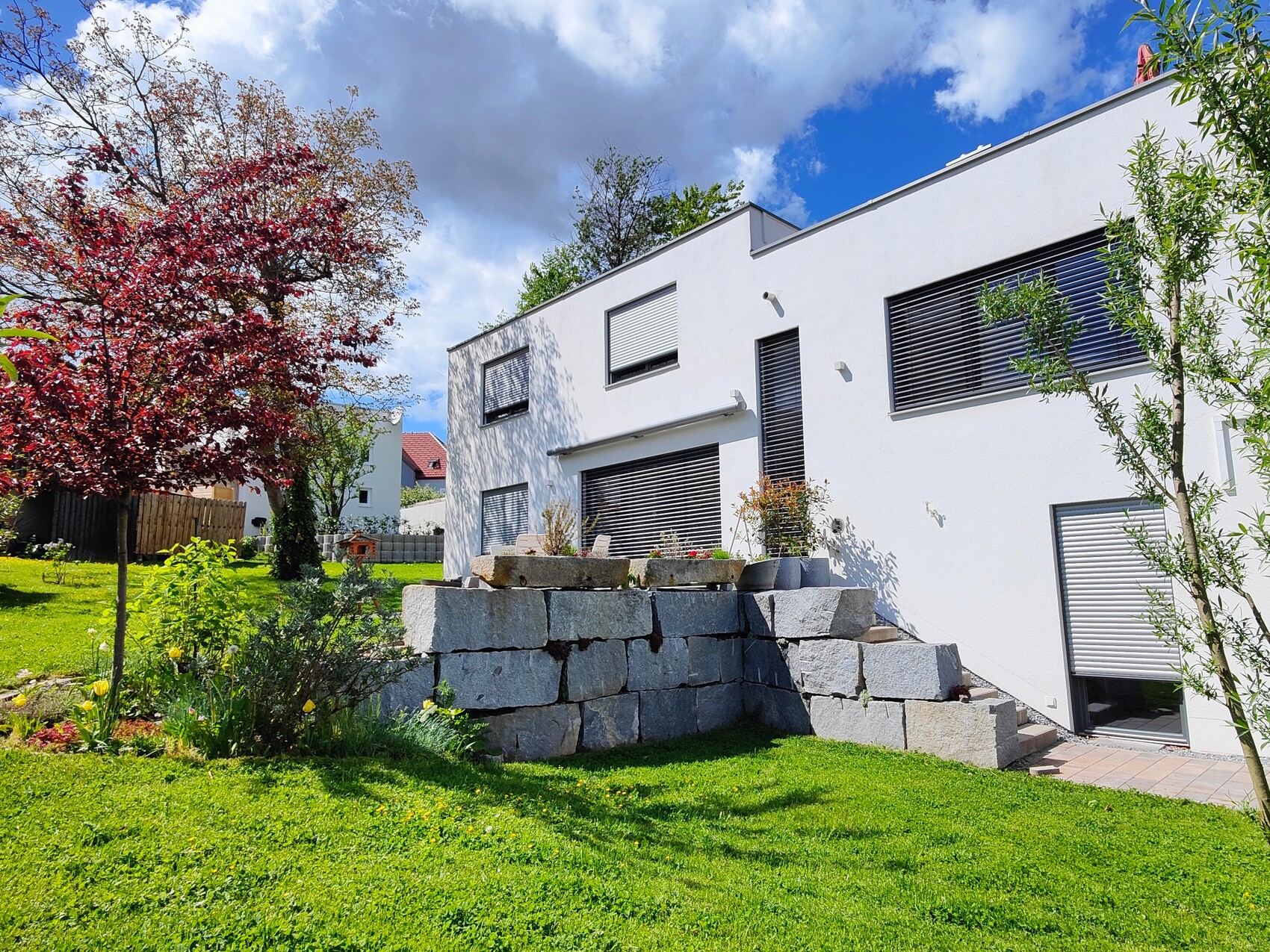 moderne-weisse-hausfassade-mit-garten-und-steinmauer-terrasse.jpg