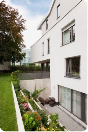 Außenansicht eines modernen weißen Mehrfamilienhauses mit Terrasse und Garten