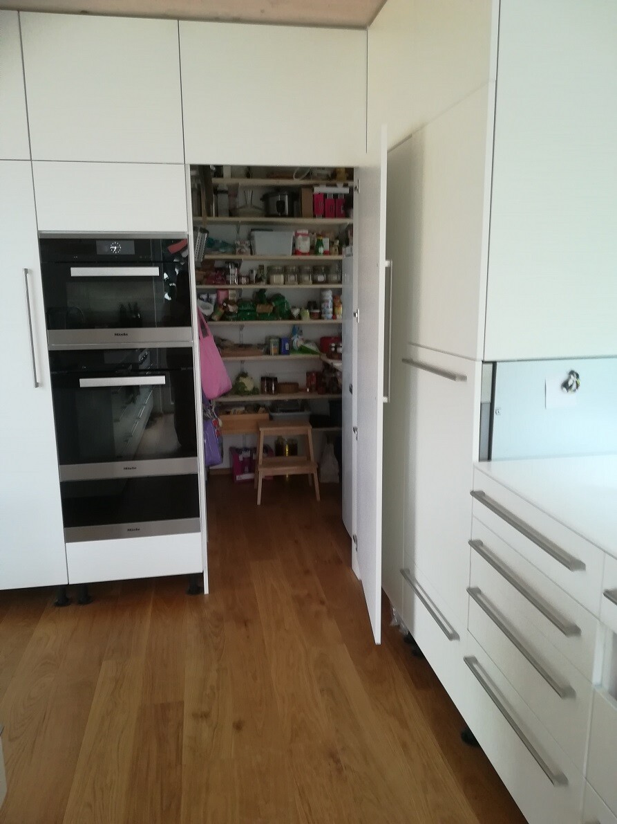 Moderne weiße Küchenzeile mit eingebauten Geräten und offenem Vorratsschrank