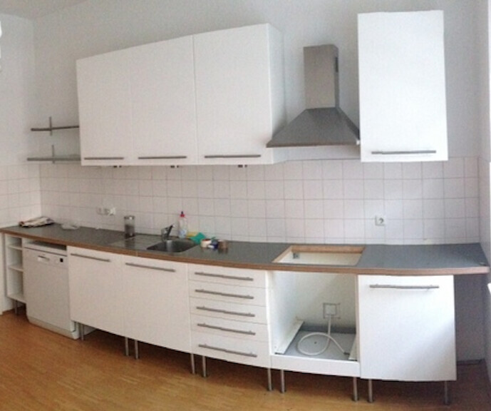 Moderne weiße Küche mit Spüle, Unterschränken und Edelstahl-Dunstabzugshaube