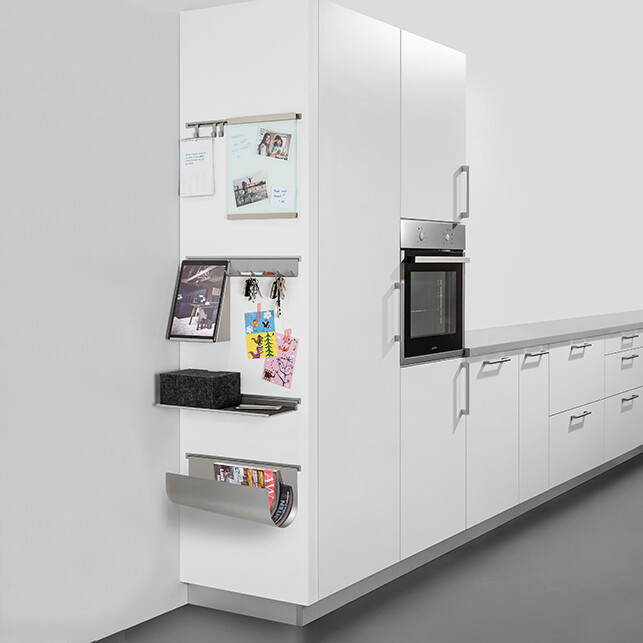 Moderne weiße Küche mit Kühlschrank, Backofen und Organizer-Elementen an der Türsäule.