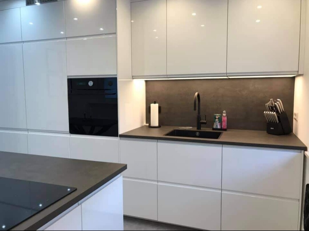 Moderne weiße Küchenzeile mit dunkler Arbeitsplatte, Spüle und Messerblock.