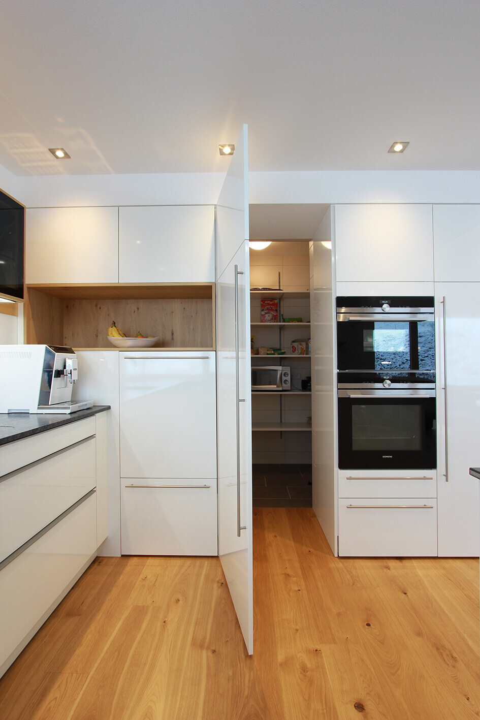 Moderne helle Küche mit offener Vorratskammer, integrierten Backöfen und Holzfußboden.