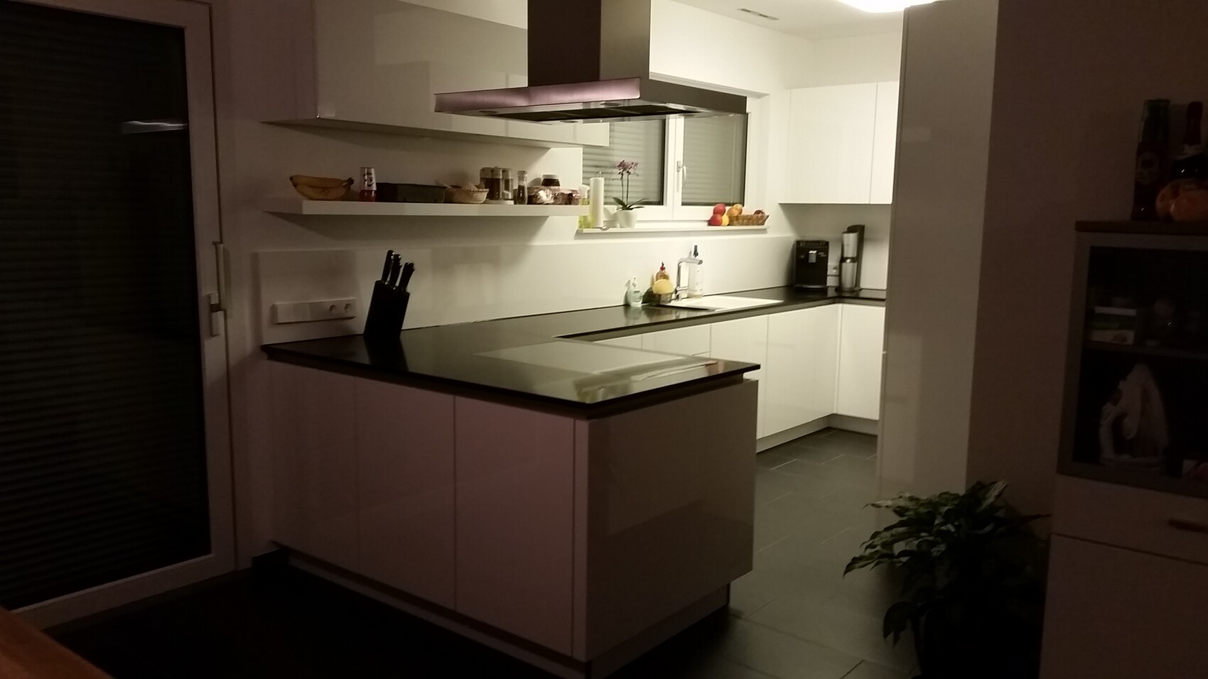 Moderne Küche mit Insel, offener Ablage, Fenster, Obstkorb und Kaffeemaschine.