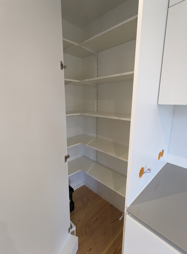 Offener weißer Küchenschrank mit mehreren verstellbaren Regalböden, leer.