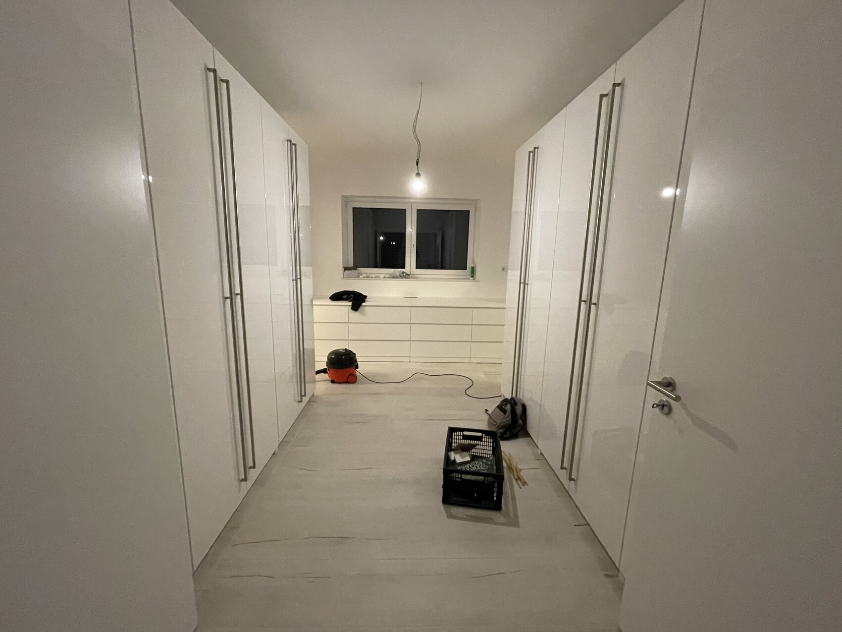 Moderne weiße Küche in einer engen Galley-Küche mit hohen Schränken beidseitig und zentraler Arbeitsfläche