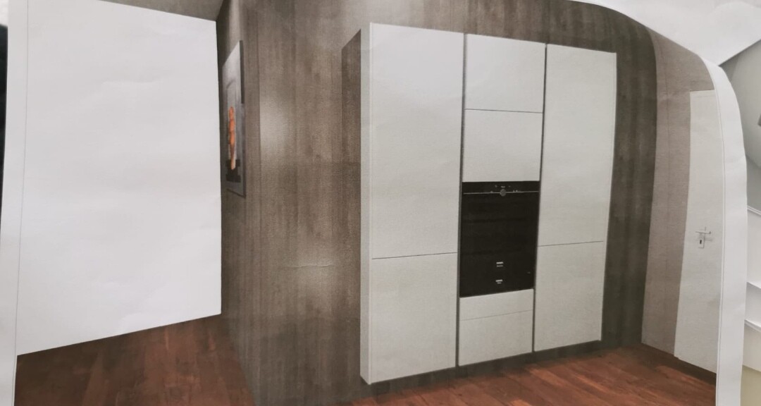 Moderne Einbauküche mit weißen Schränken und integriertem Backofen auf Holzboden.