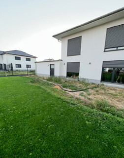 Moderne weiße Hausfassade Außenansicht mit Fensterläden und grünem Garten