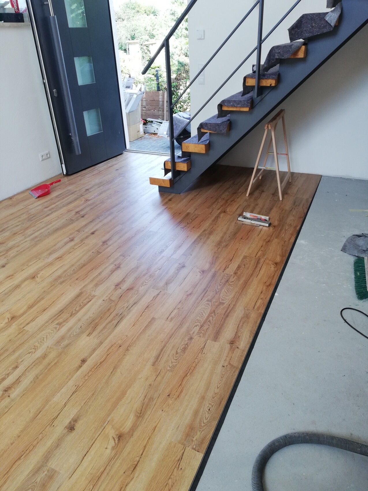 Neuer Holzboden, Treppe mit schwarzem Metallrahmen und Holzstufen, Werkzeuge liegen bereit.
