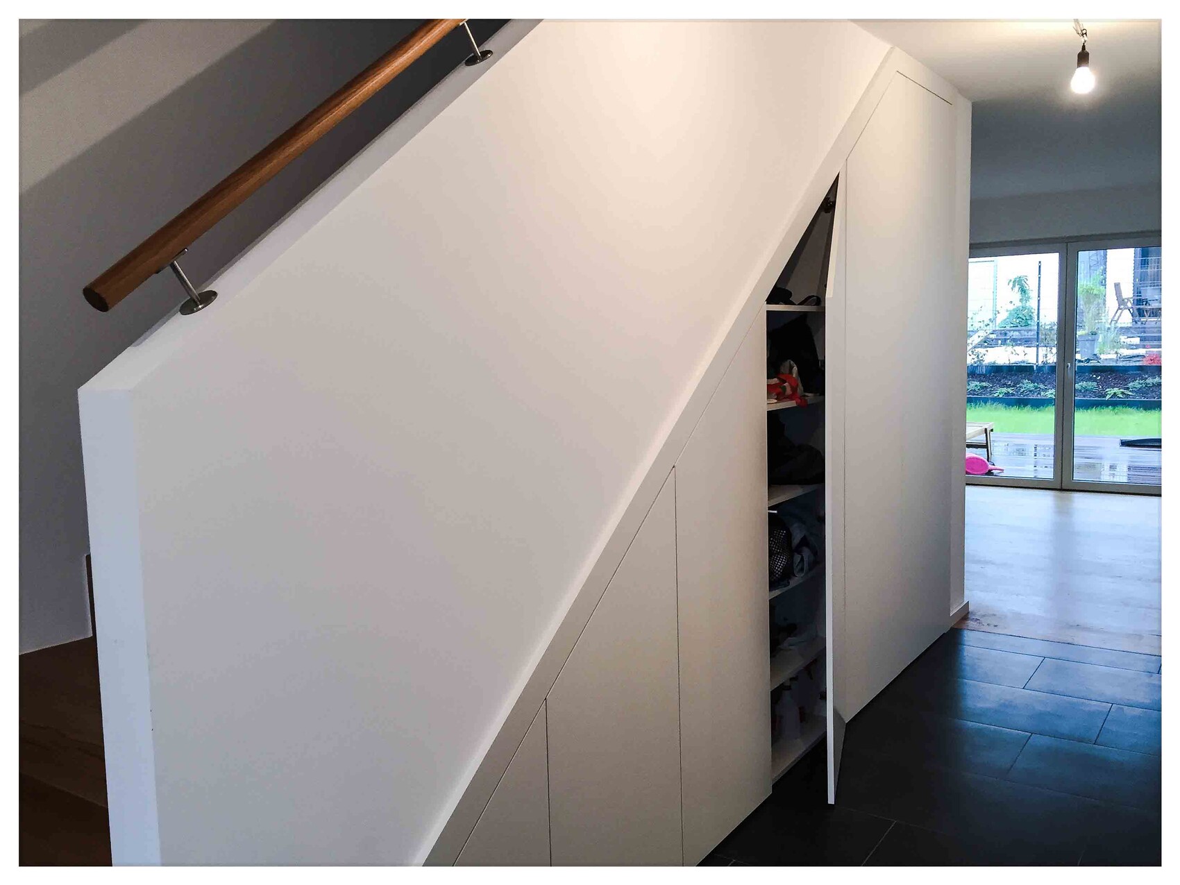 Weißer Einbauschrank unter der Treppe, offenes Kleiderschrankfach im modernen Flur